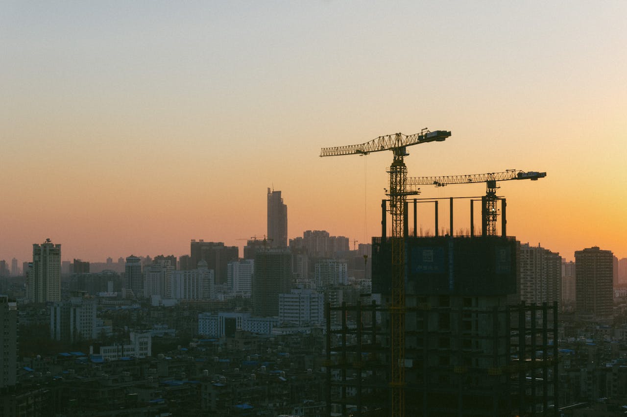 Silhouette of construction cranes against a sunset backdrop in Wuhan, China.